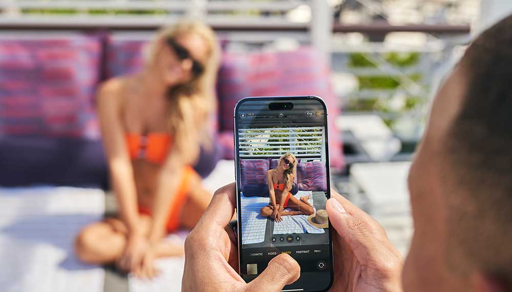 man taking woman’s photo on a phone in a caban at Kimpton Hotel Palomar South Beach
