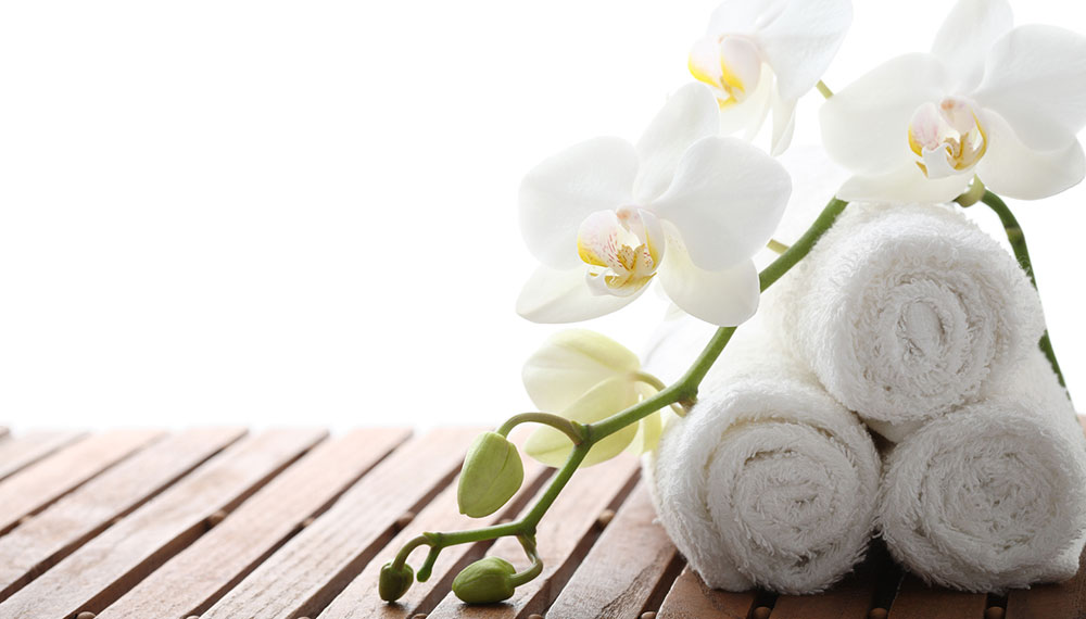 white orchids leaning against white rolled towels