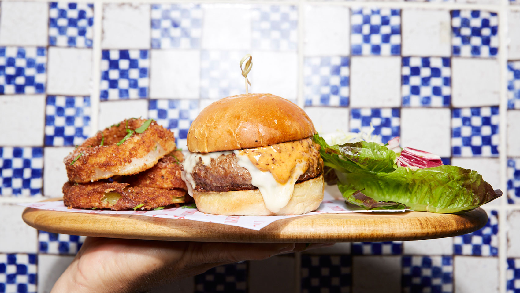 Hand holding plate with Burger, Onion rings